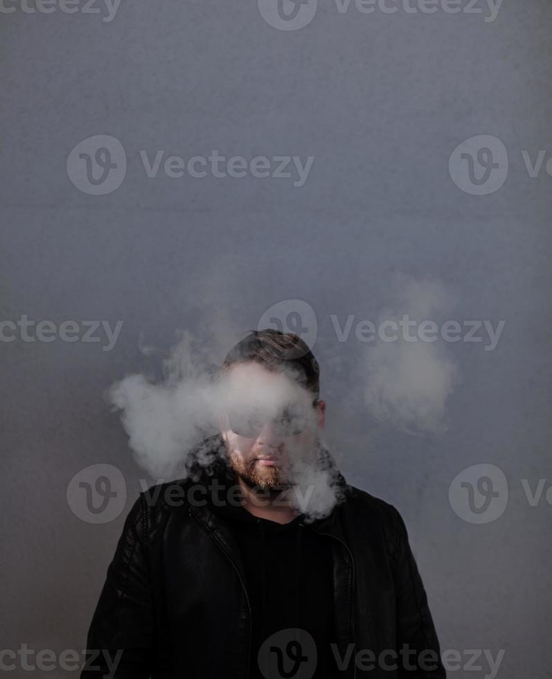 man in a leather jacket stands in a cloud of smoke photo