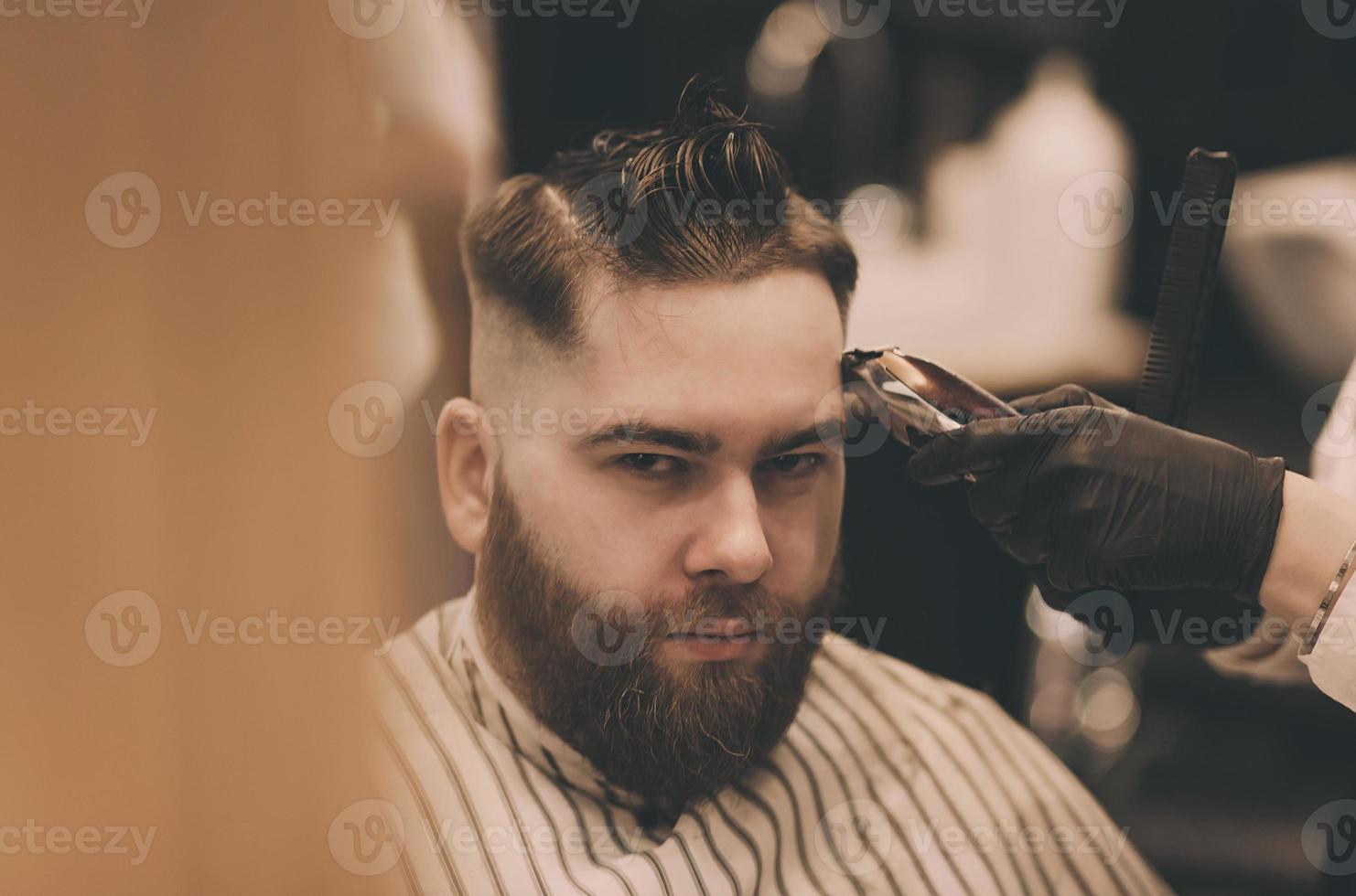 Young man with trendy haircut at barber shop photo