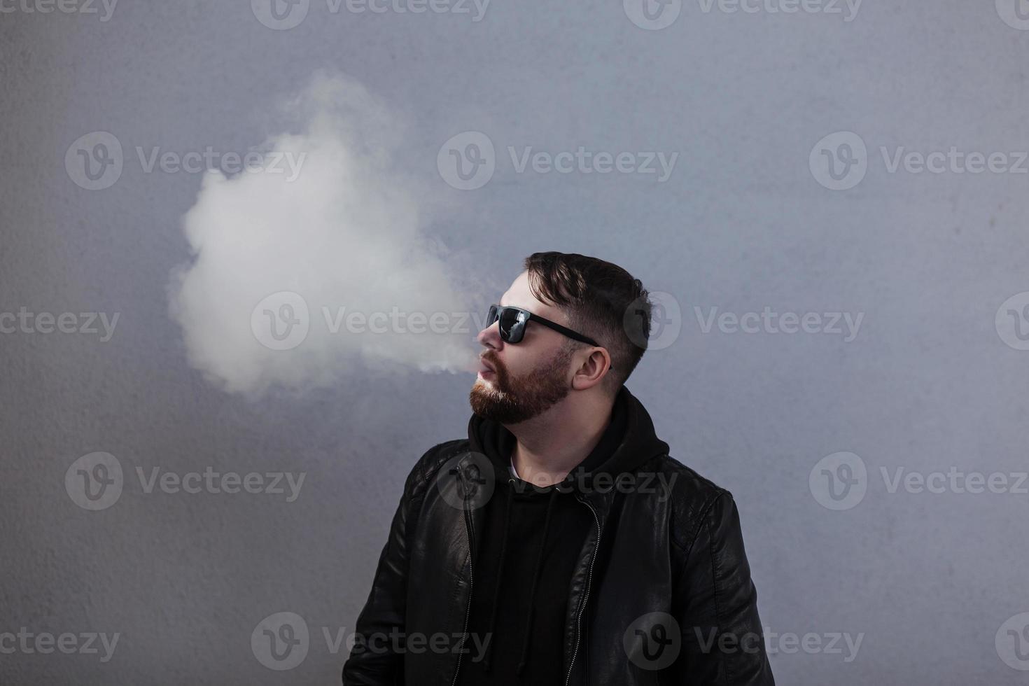 hombre elegante en chaqueta con humo cerca de la pared foto