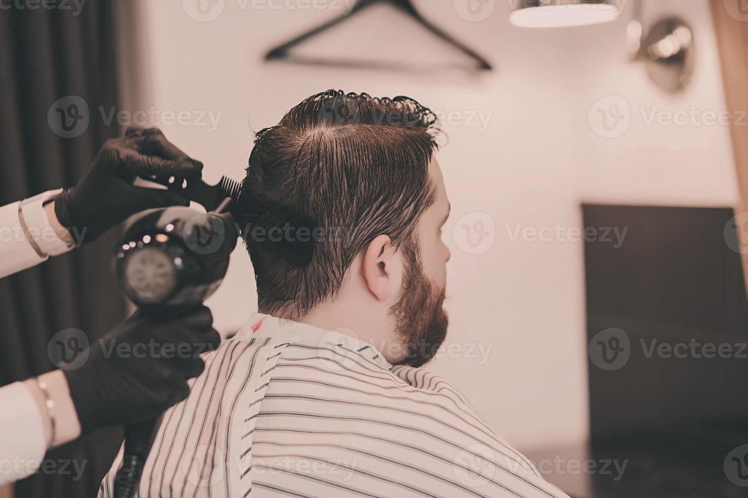 Barber in black gloves dries a man's head photo