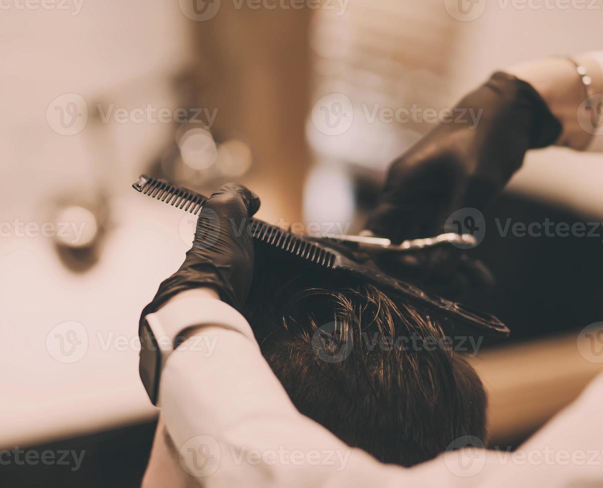 Barber with a comb and scissors cuts the client's photo