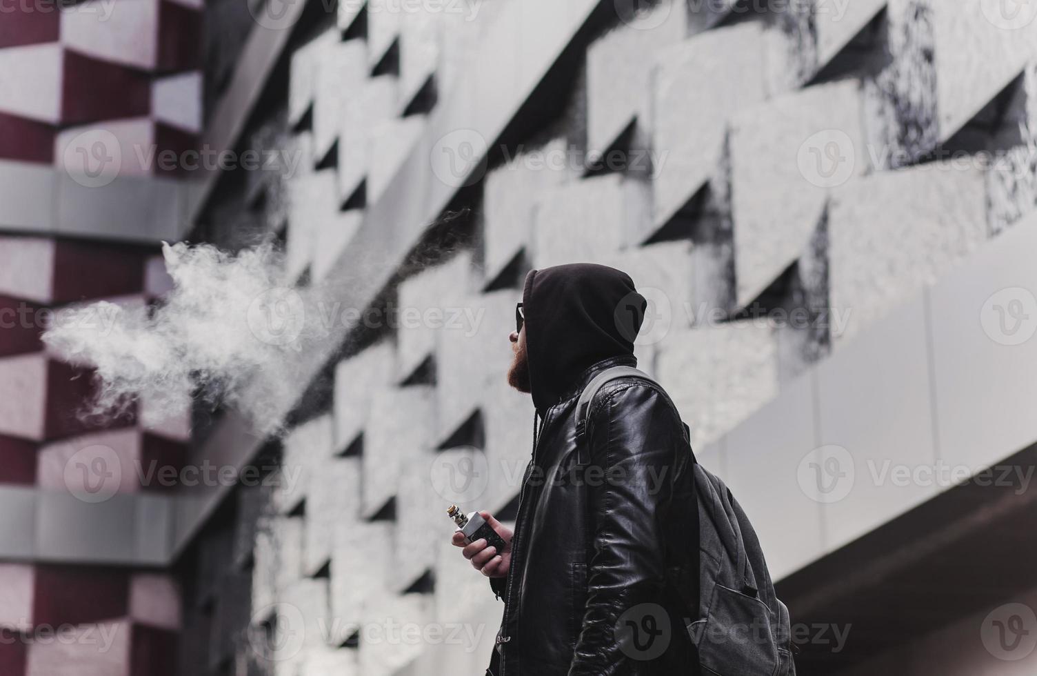 apuesto joven blanco en el capó vapeando foto