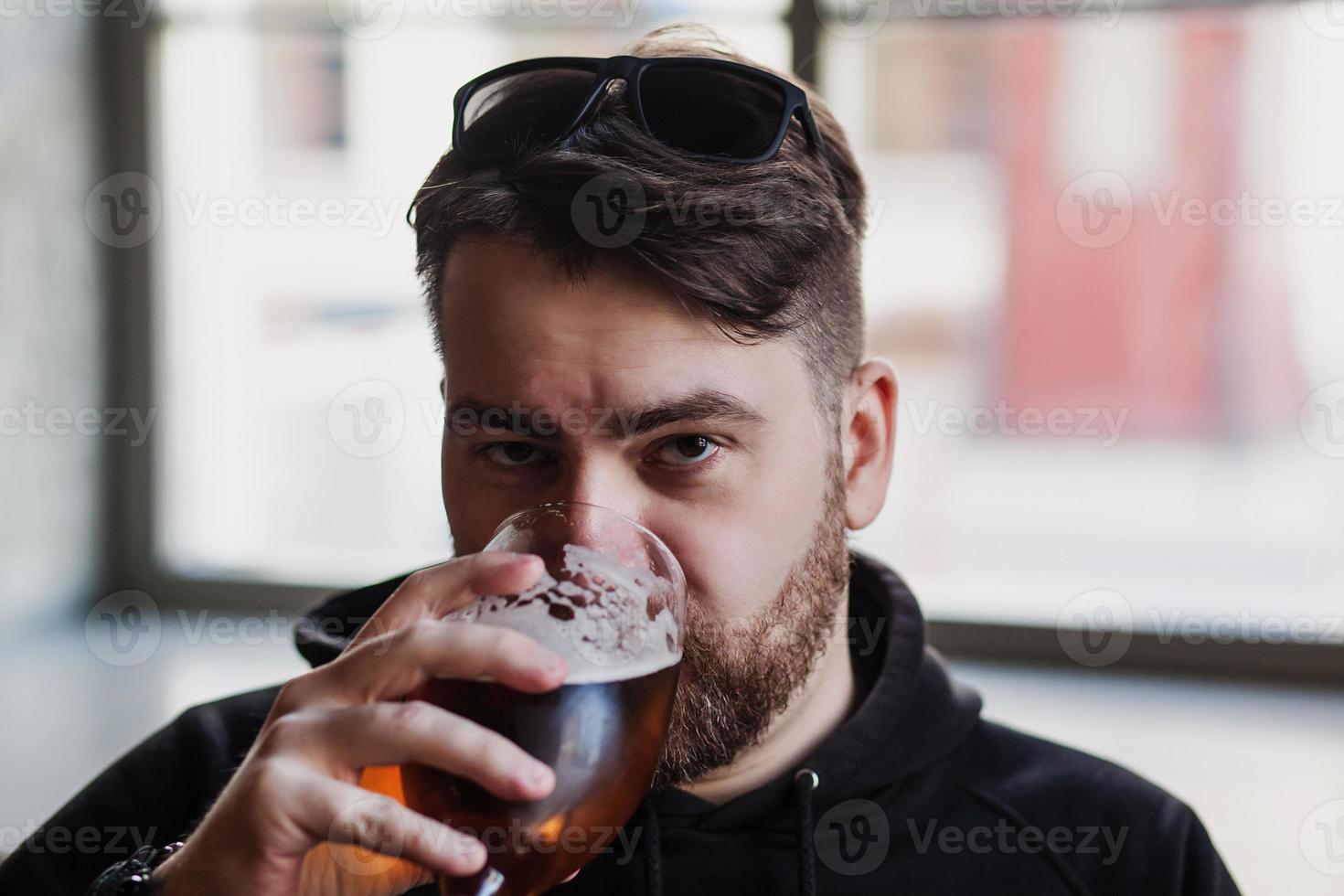 Bearded man drinks beer in a bar photo