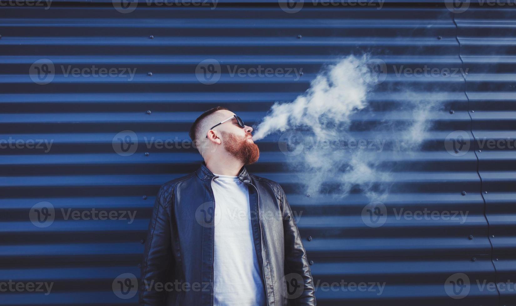 hombre con barba vapeando al aire libre foto