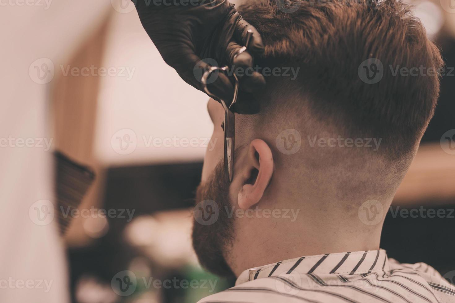 hombre barbudo brutal cortándose el pelo de la barba foto