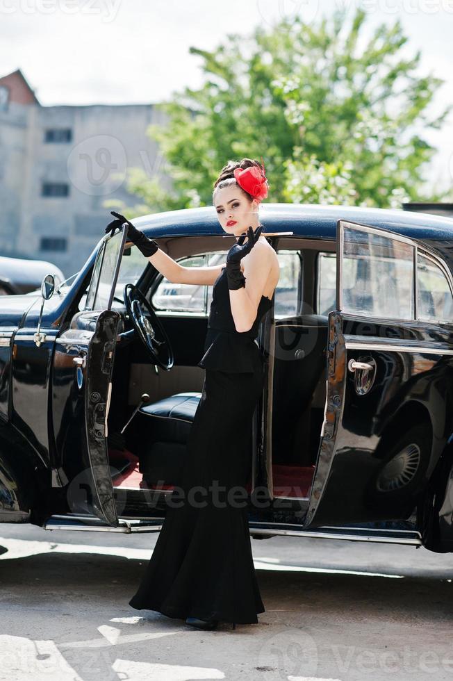 retrato de hermosa modelo de chica de moda morena sexy con maquillaje brillante en estilo retro cerca de coche vintage con un cigarrillo en la mano. foto