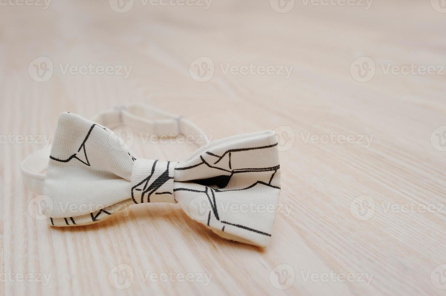 White hi tech bow tie on light wooden background photo