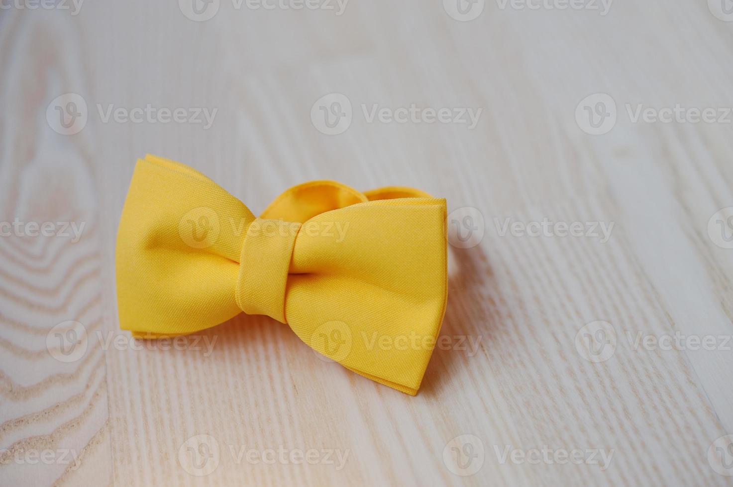 Yellow bow tie on light wooden background photo