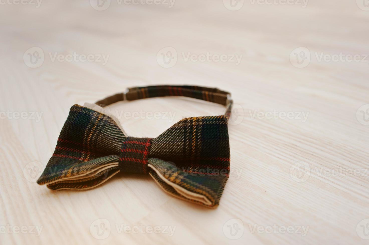 Cotton checkered bow tie on light wooden background photo