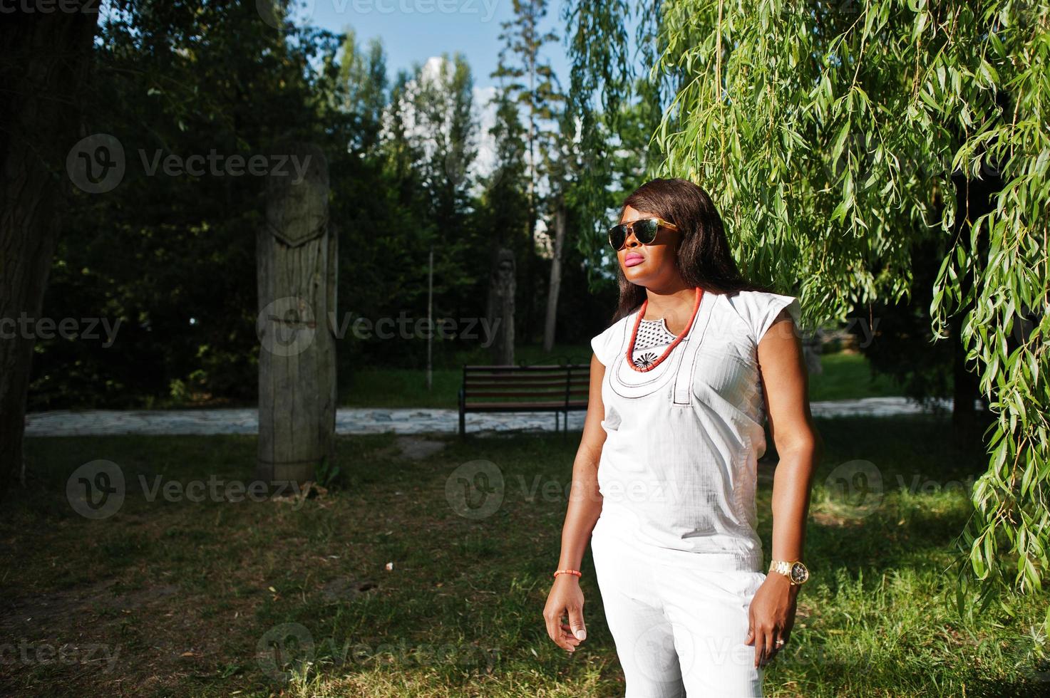 Portrait of african woman at sunglasses on sun light at green park photo