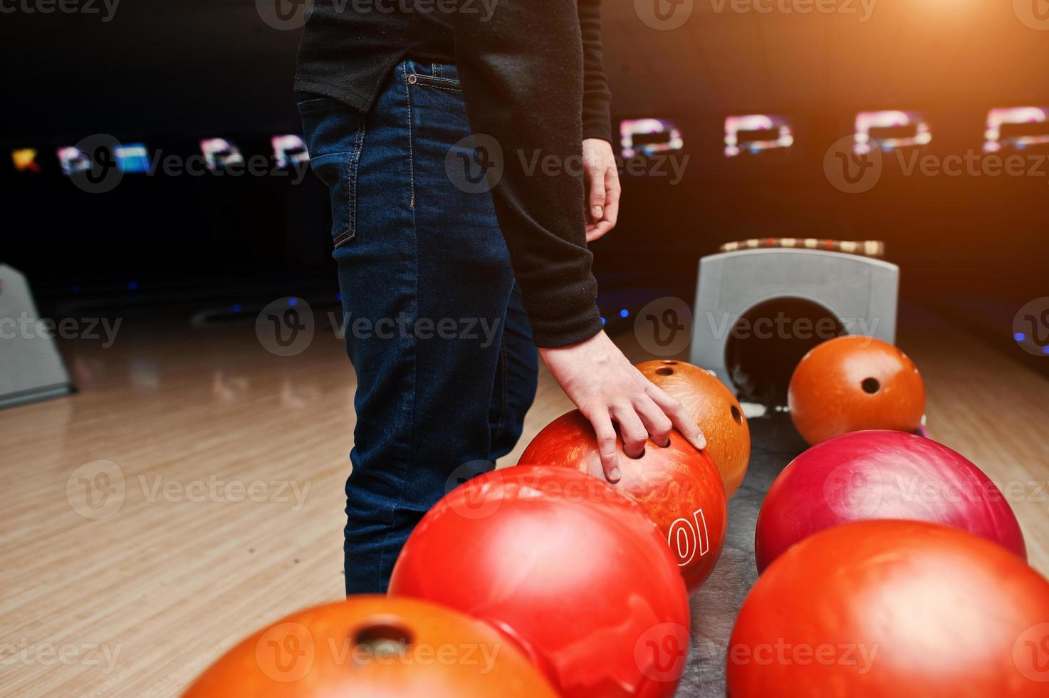 primer plano de la mano del jugador de bolos tomando la bola roja del elevador del tazón foto