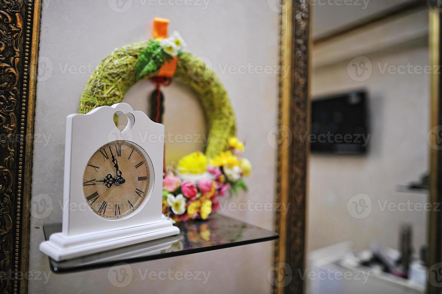 Decorated old vintage clock near mirrors at make up saloon photo