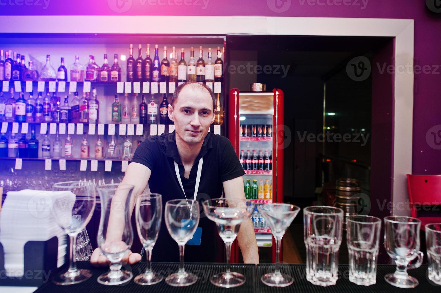 Bartender at the bar in the club near set of glasses photo