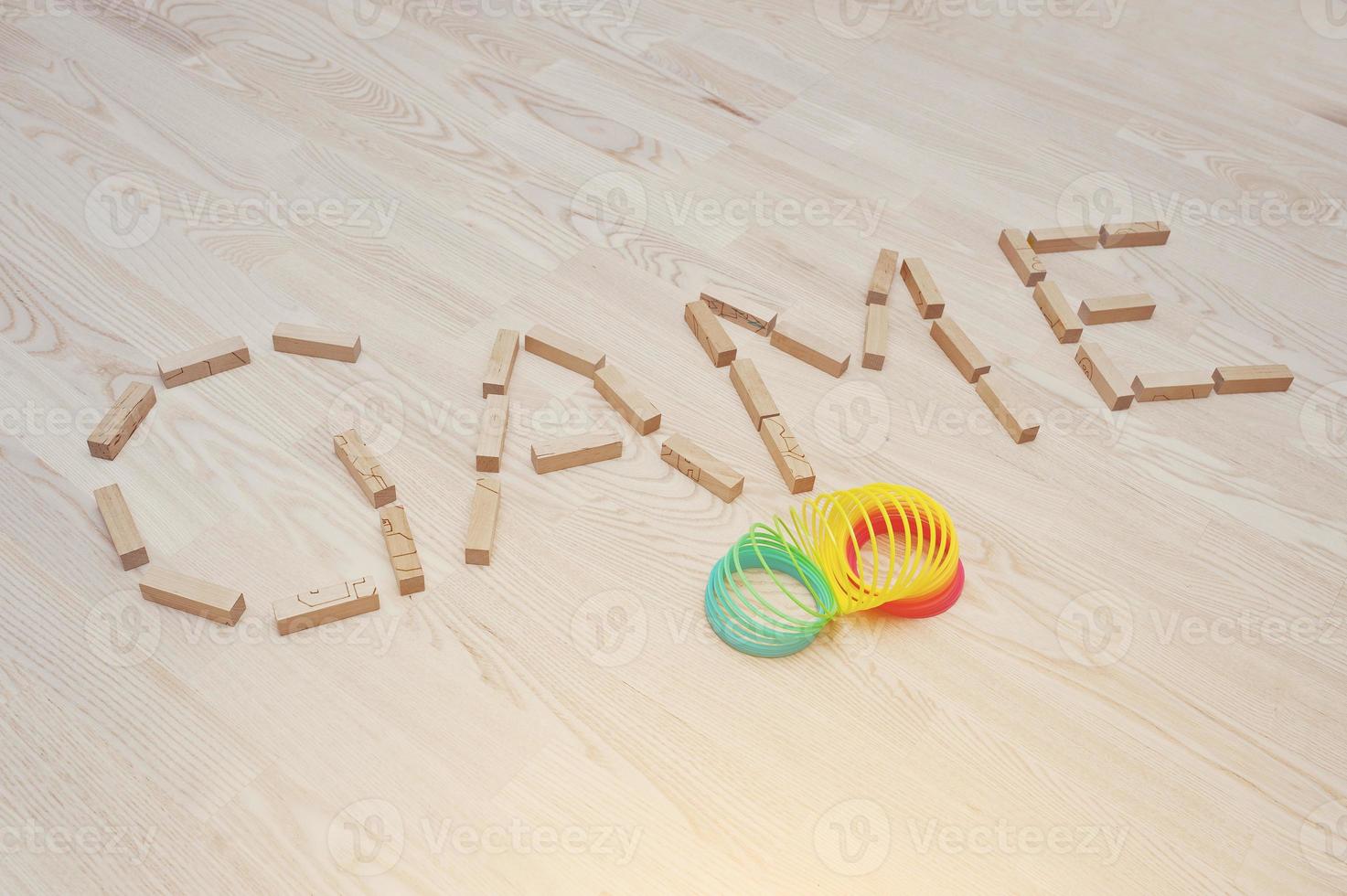 The word Game of wooden blocks on parquet background with rainbow spiral spring photo