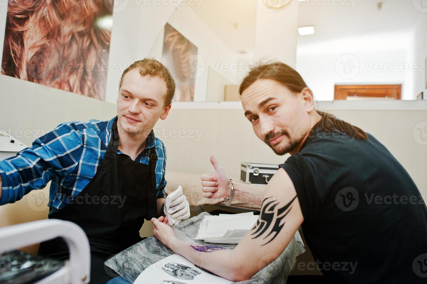 Tattoo master make tattoo for rocker man at tattoo salon photo