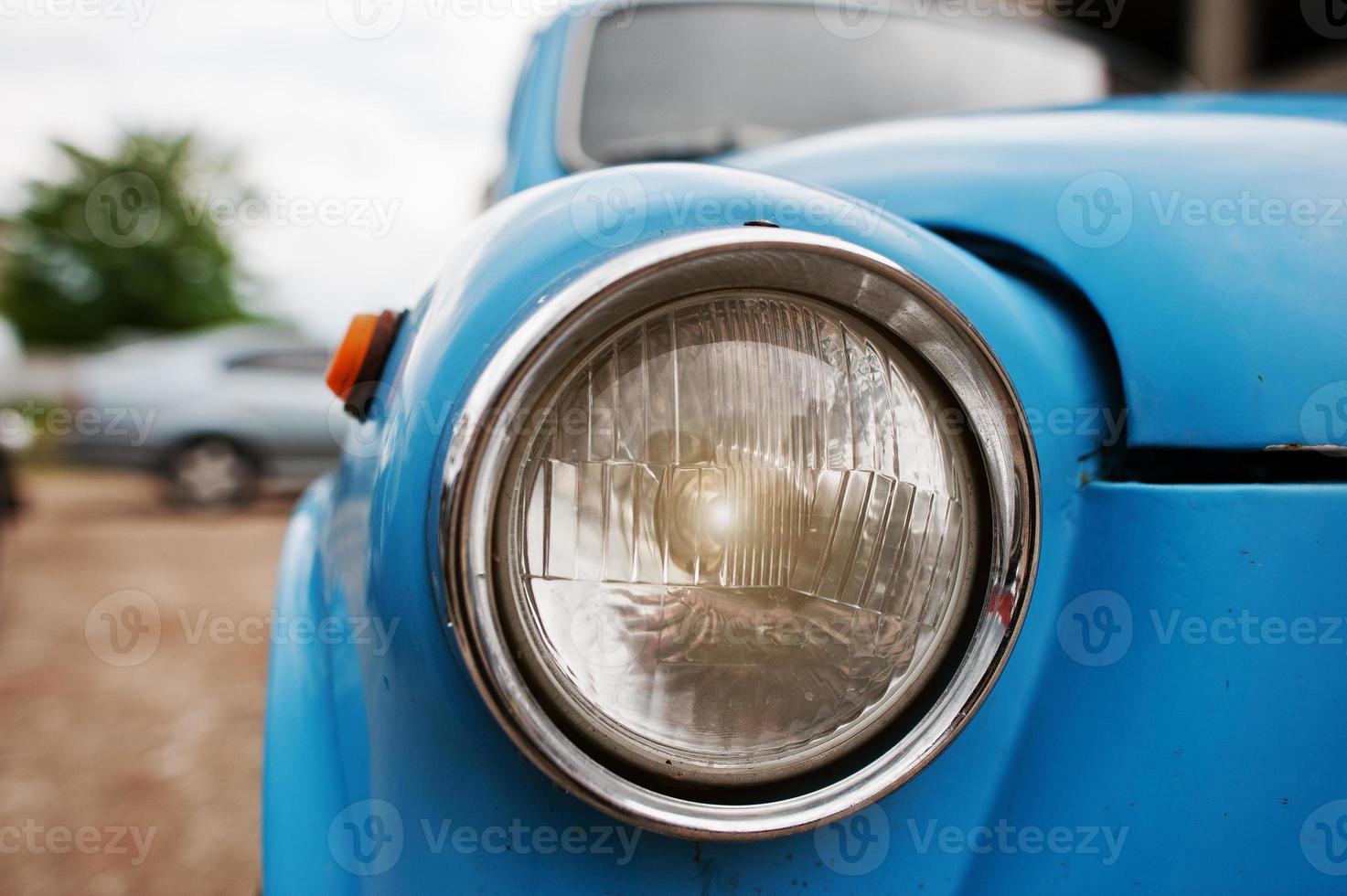 Old vintage car headlight close up at blue car. photo