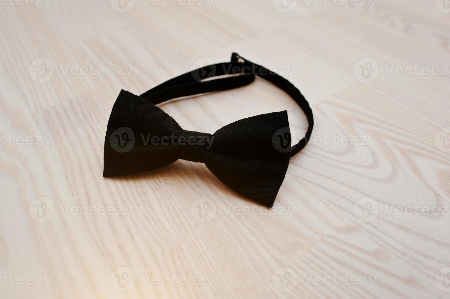 Black cotton bow tie on light wooden background photo