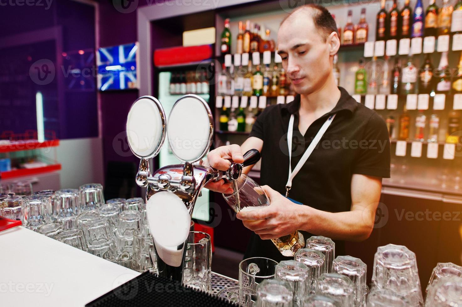 el camarero vierte una cerveza en el bar del club foto