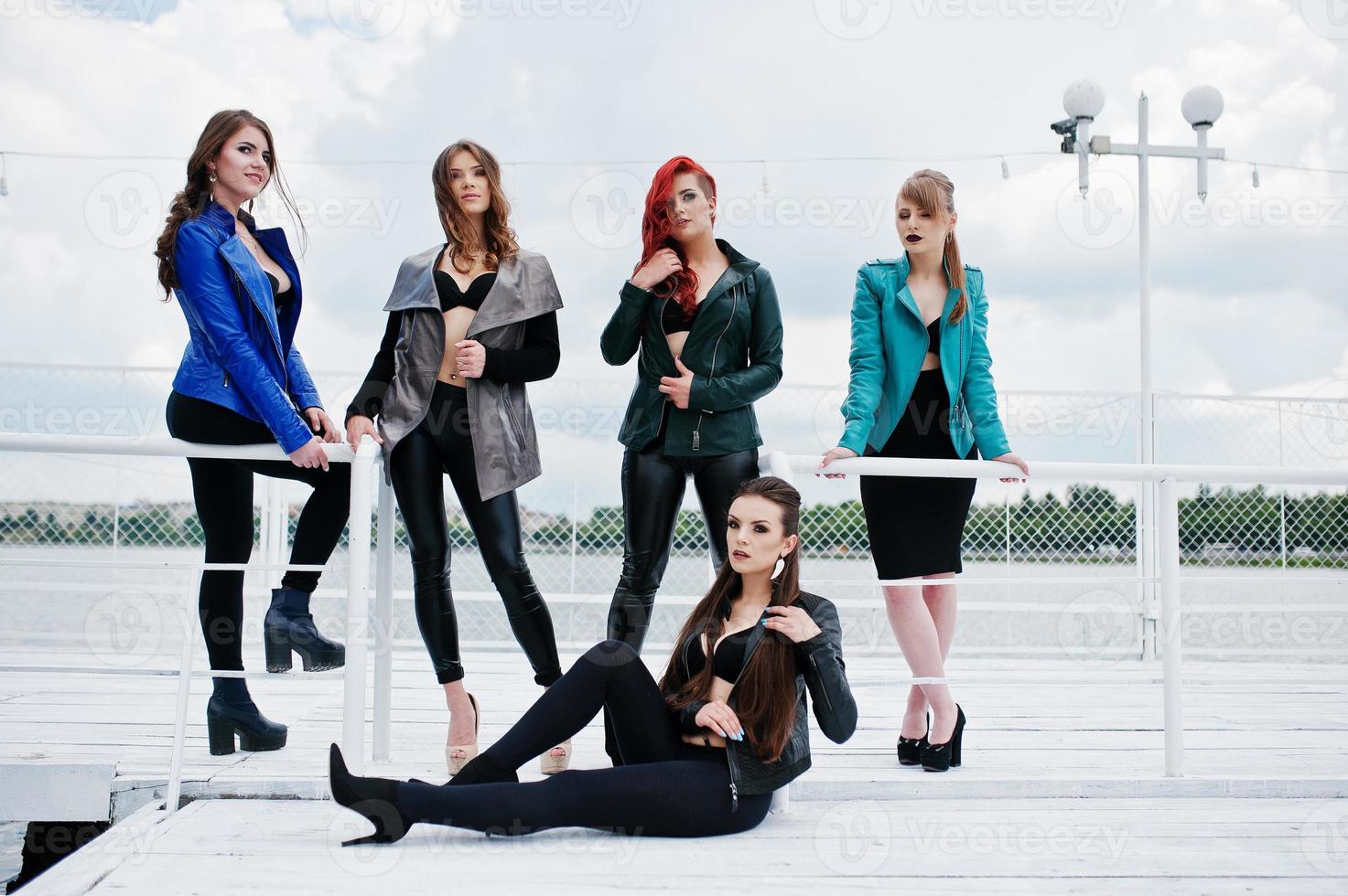 Group of sexy models girls in black bra and leather jackets on the dock photo