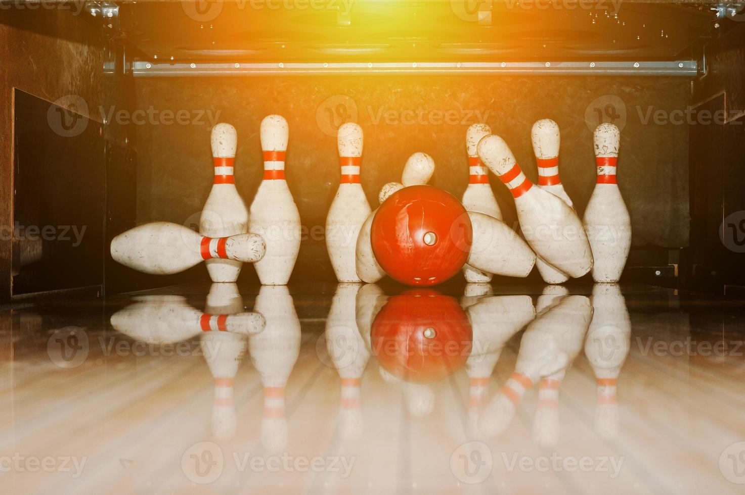 Ten white pins in a bowling alley with ball hit photo
