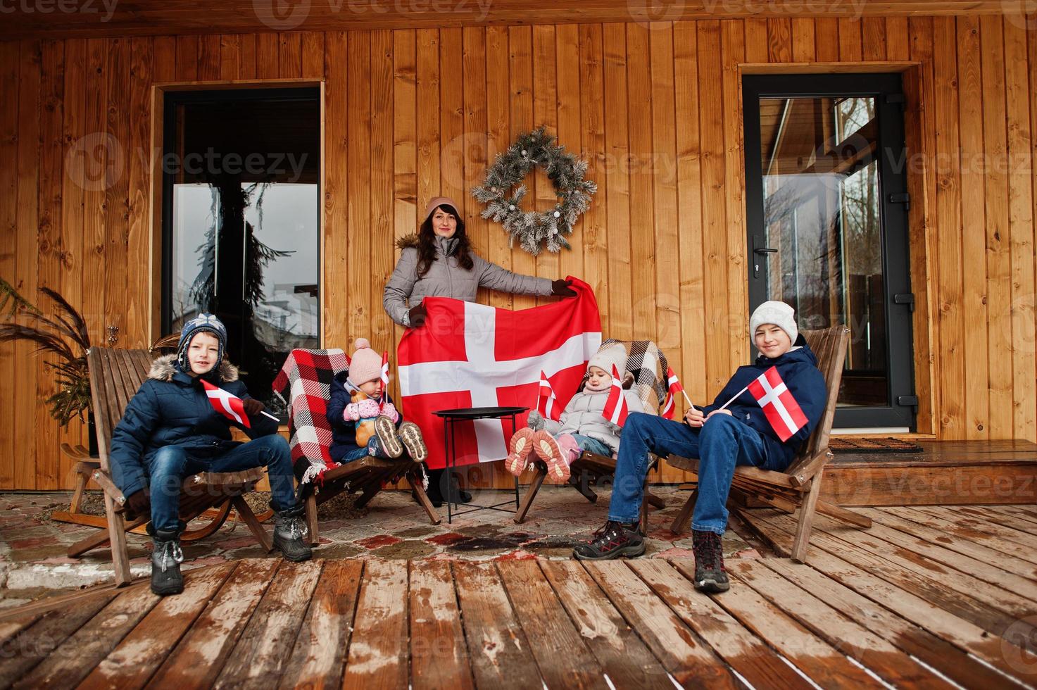 Family with Denmark flags near they wooden house. Travel to Scandinavian countries. Happiest danish people's . photo