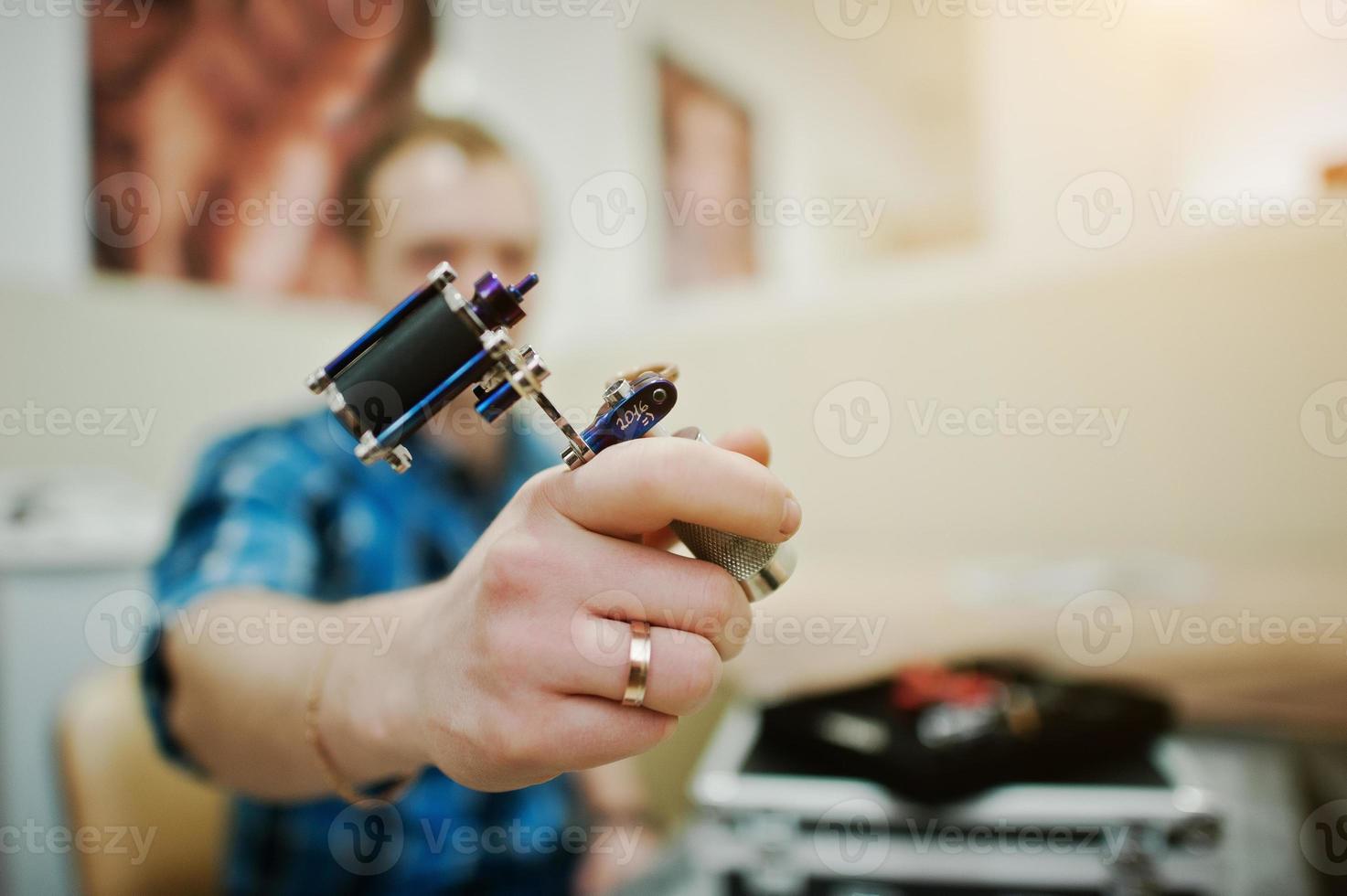 vista de cerca de la máquina de tatuaje en la mano del maestro del tatuaje foto