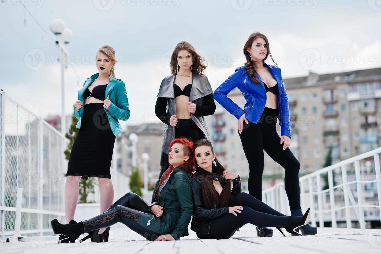 Group of sexy models girls in black bra and leather jackets on the dock photo