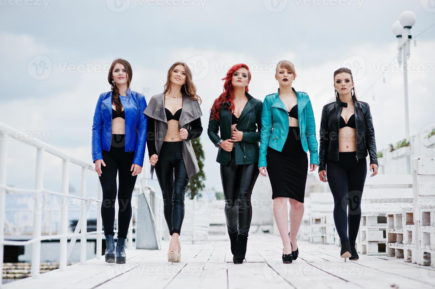 Group of sexy models girls in black bra and leather jackets on the dock photo