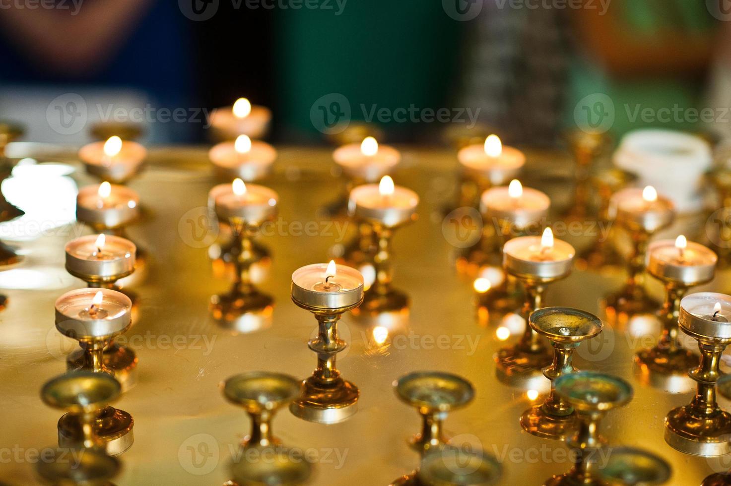 Row of burning circle candles on a golden stand at church photo
