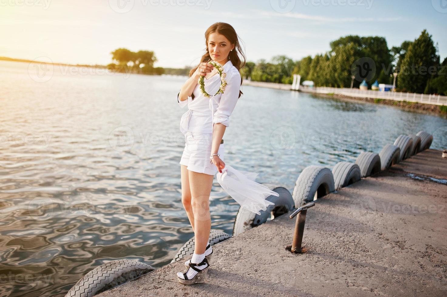 chica en despedida de soltera con corona y velo lago de fondo al atardecer foto