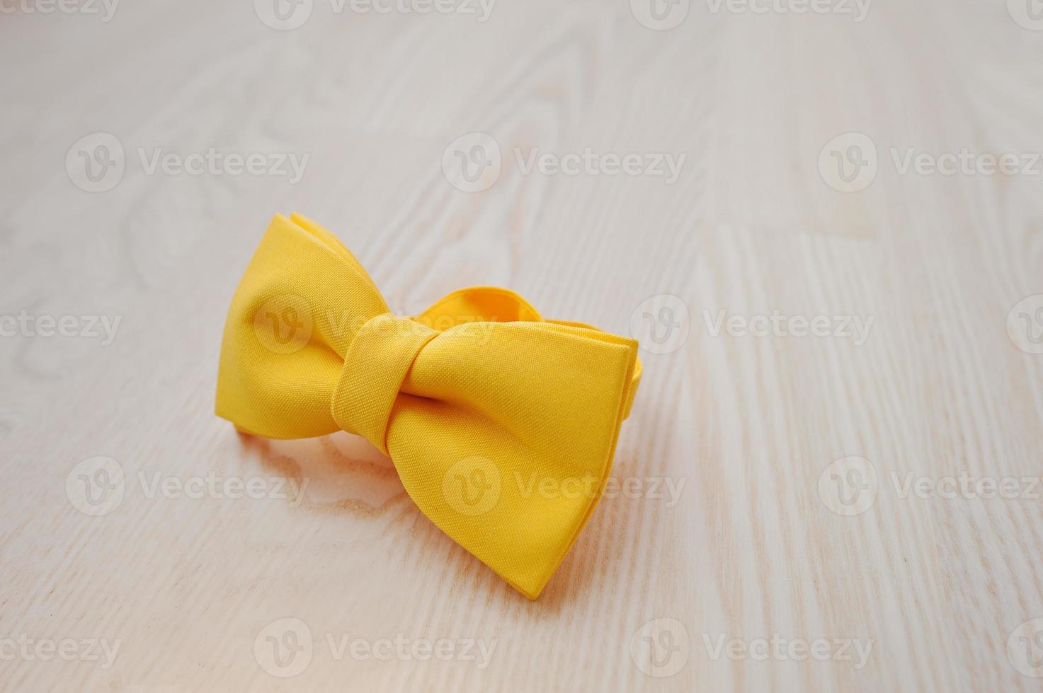 Yellow bow tie on light wooden background 5975788 Stock Photo at Vecteezy