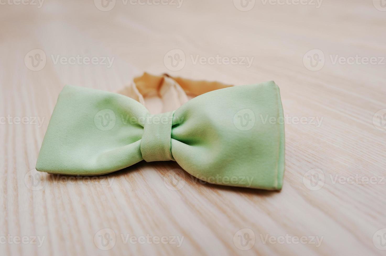 Lime silk bow tie on light wooden background photo