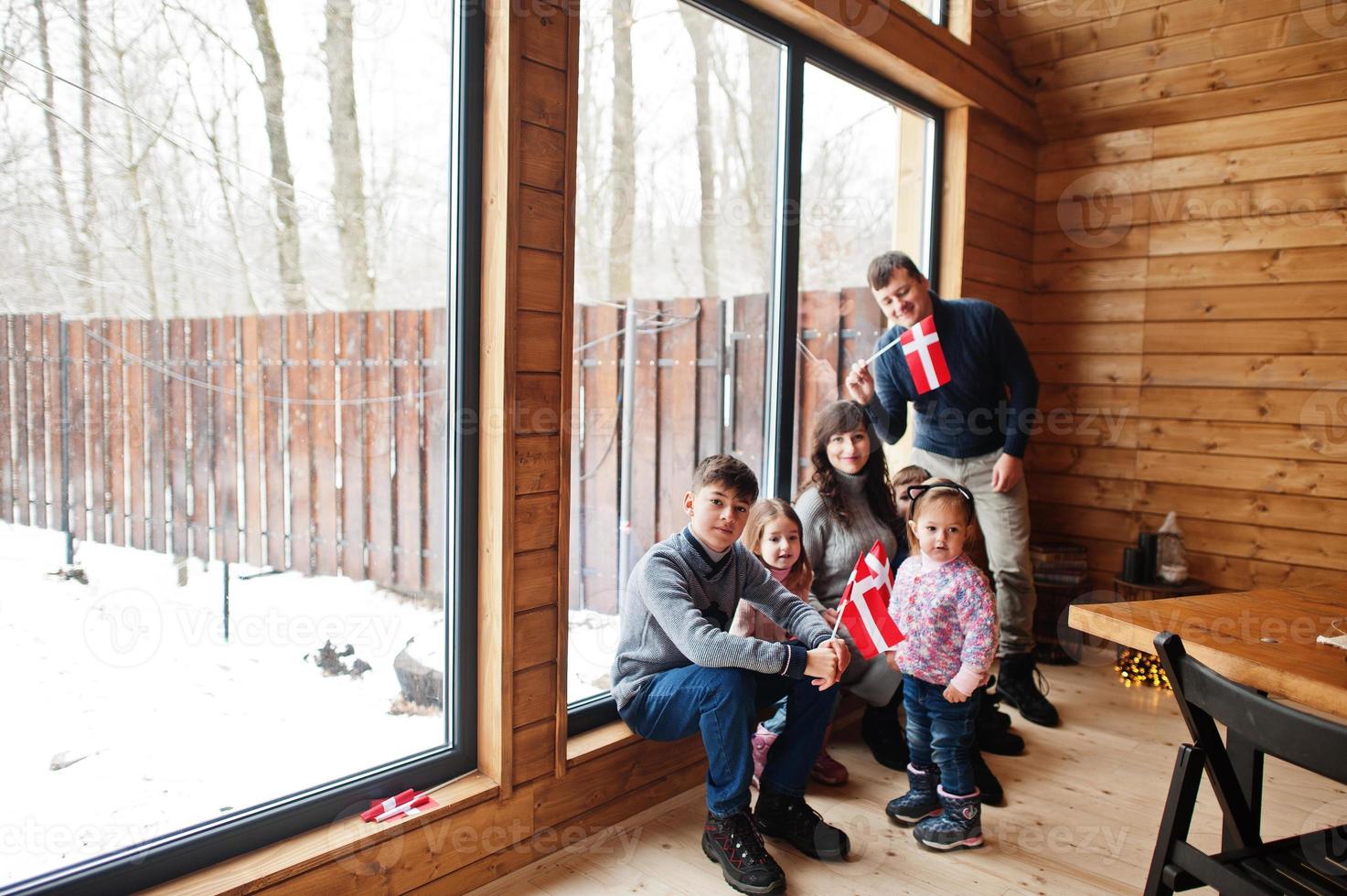 familia con banderas de dinamarca dentro de una casa de madera. viajar a países escandinavos. los daneses más felices. foto