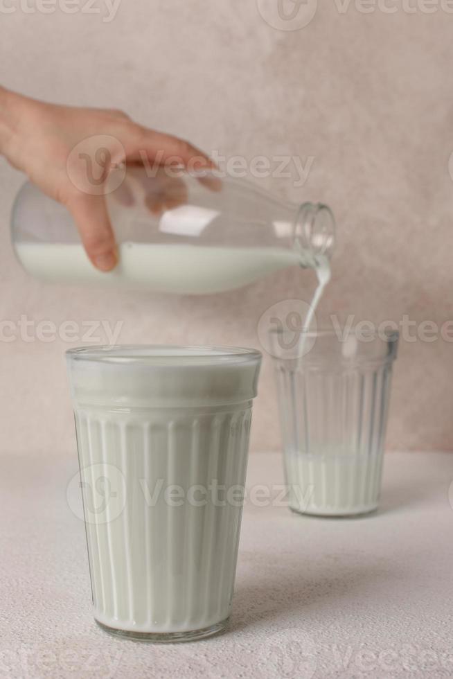 Two glasses of milk. Milk pouring from the bottle into glass. Copy space. photo