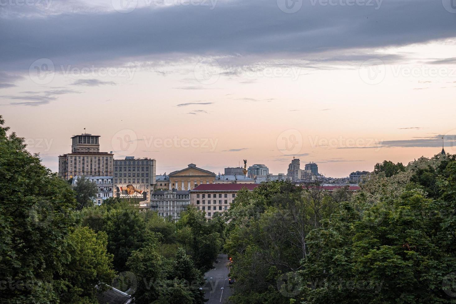 camino rural con el horizonte de la ciudad de kiev y monumento contra el cielo nublado foto