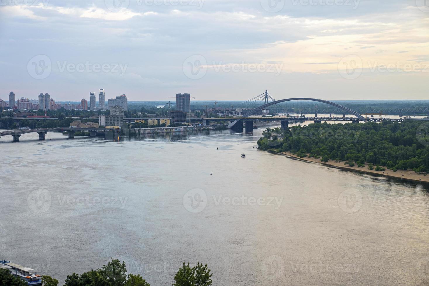 paisaje de la ciudad con puentes sobre el río dnipro contra el cielo nublado foto