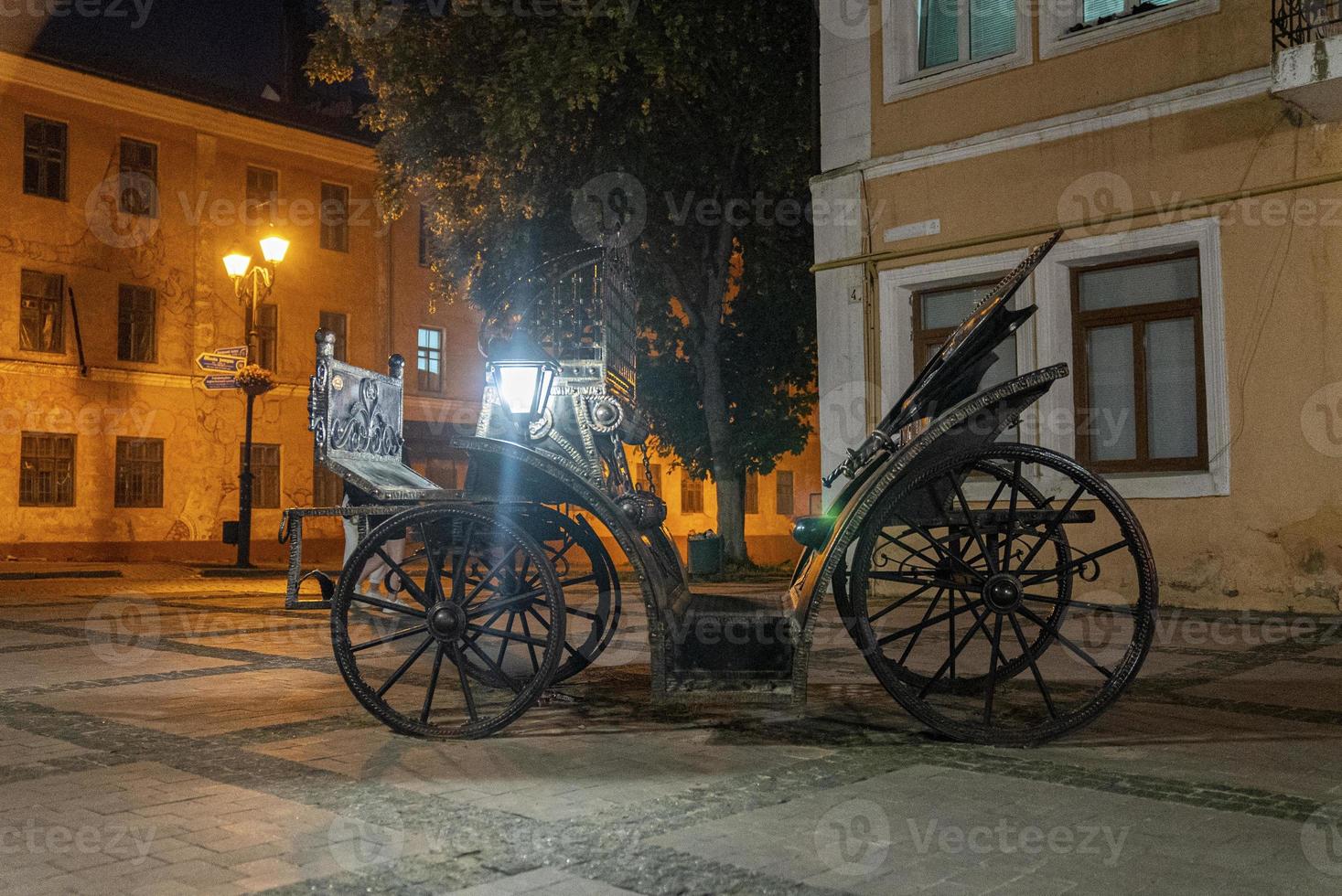 Retro ancient metallic carriage on residential alley during nighttime photo