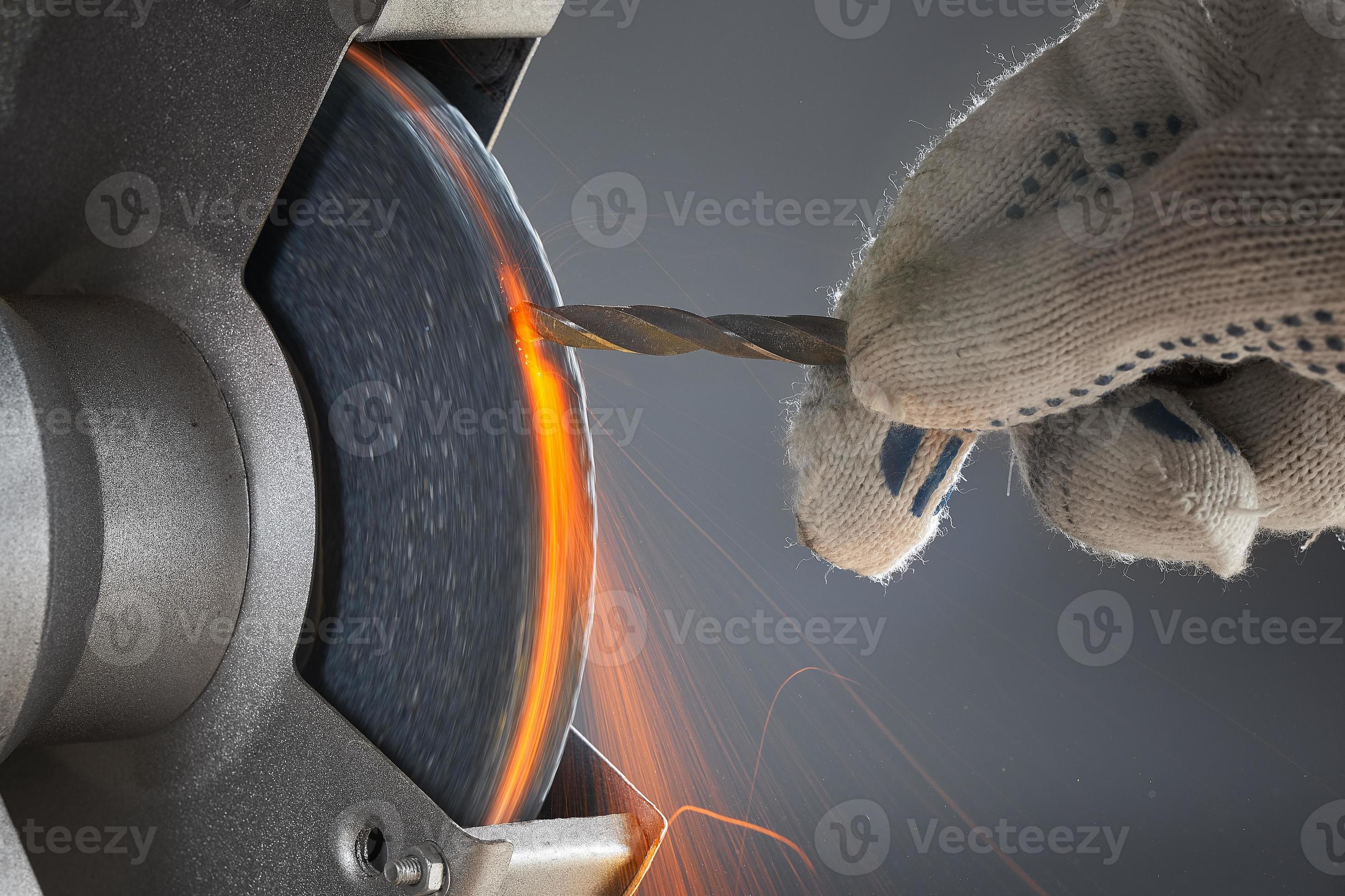 The hand wearing a work glove of man regrinding the drill tool for