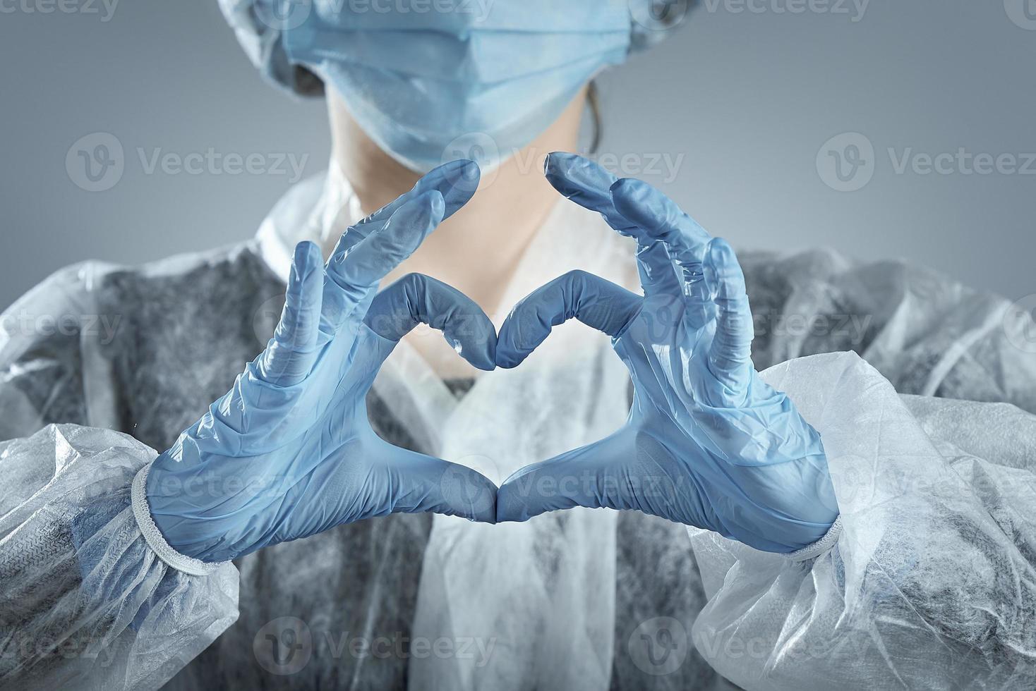 Woman in medical mask and hands in latex glove shows the symbol of the heart. photo