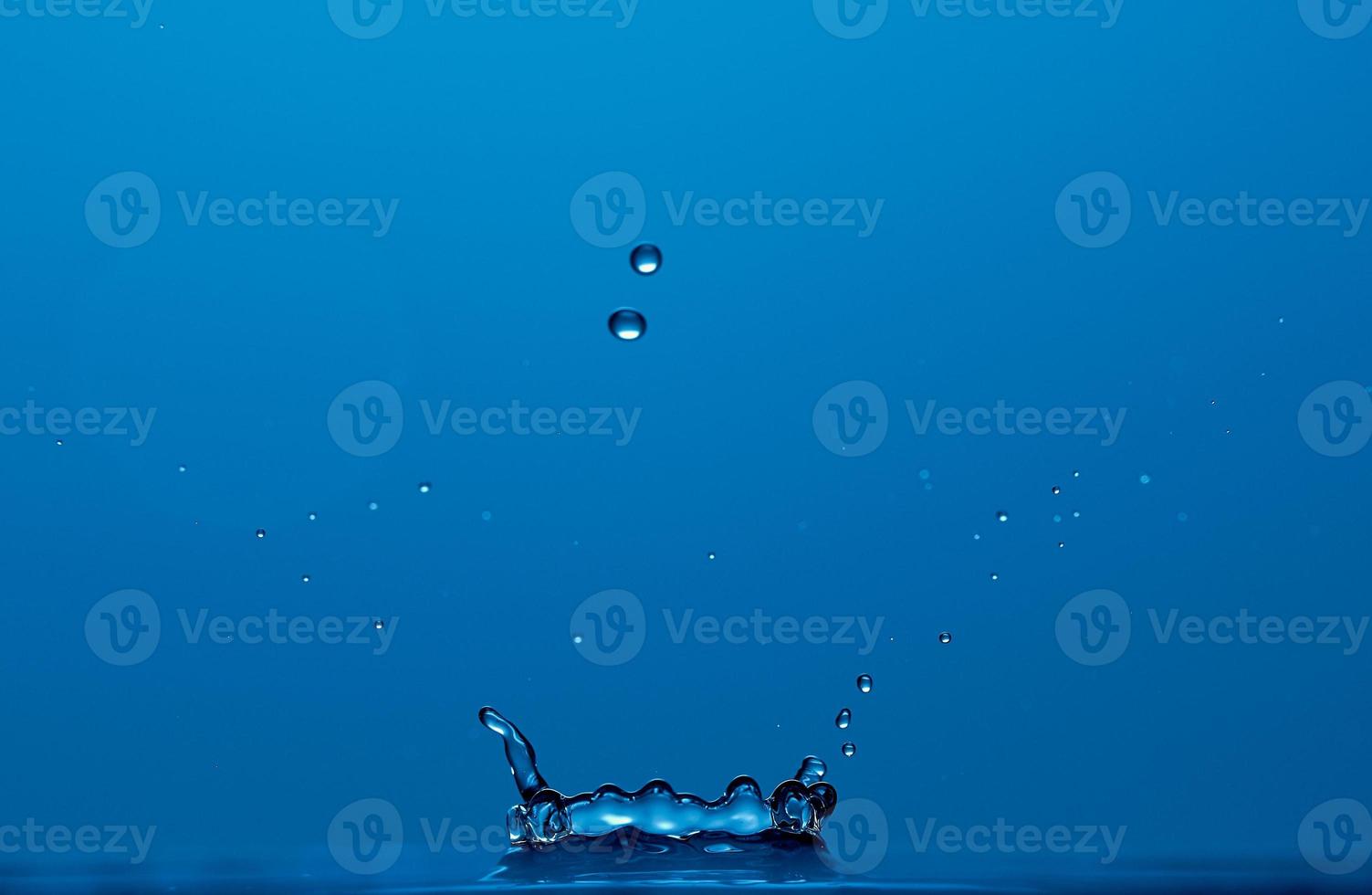 Pure clear water splash like a crown isolated on blue background. Photo with copy space.