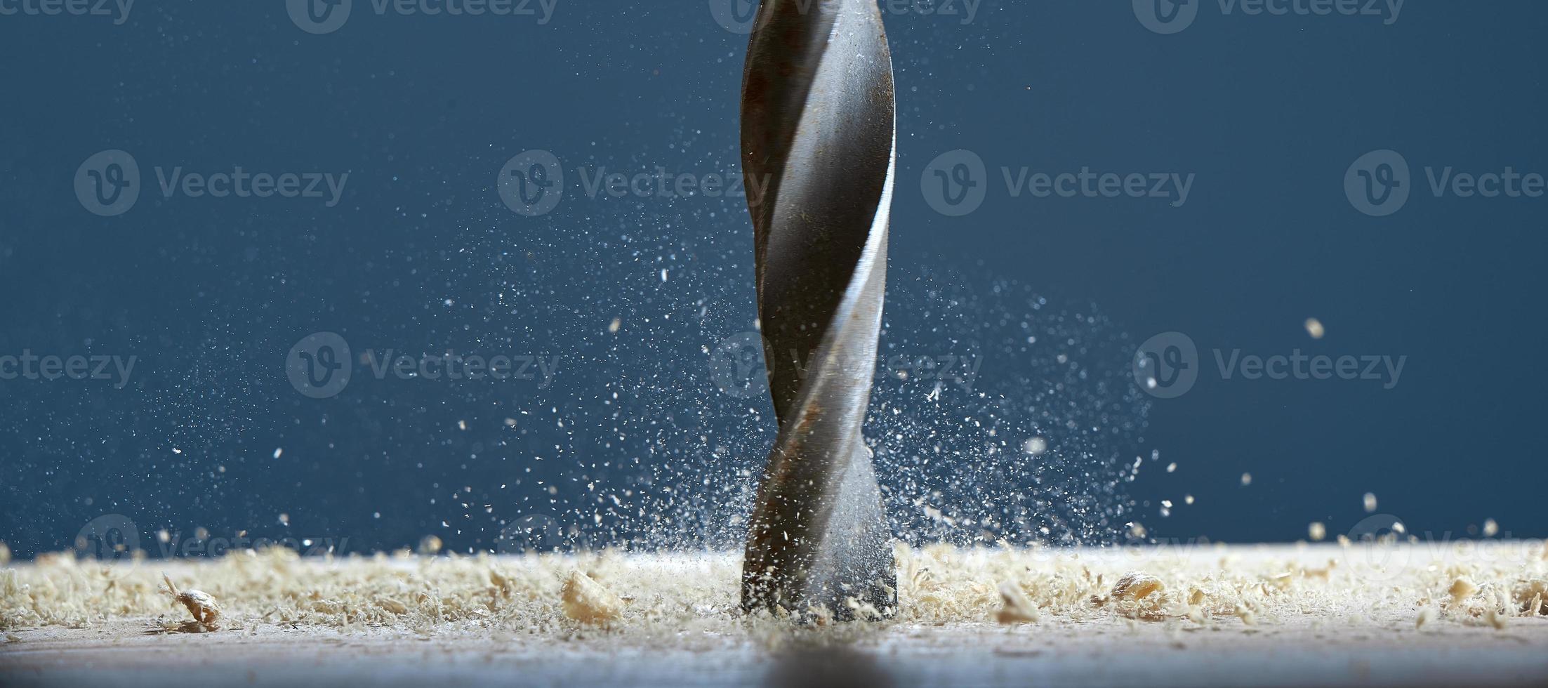 Drill bit in the center of the frame. Wood drill bit in the blur with shaving on a gray background. photo