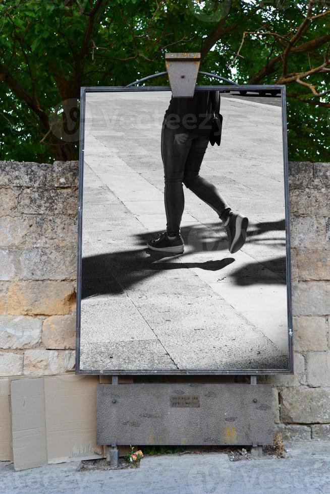 tablón de anuncios para la publicación de carteles. niña caminando con sombra alargada en blanco y negro. blanco y negro. sombra y luz, silueta de niña foto