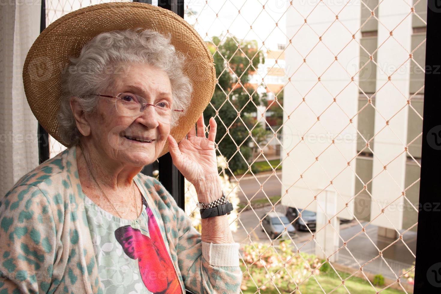 anciana en casa mirando por la ventana de su apartamento foto