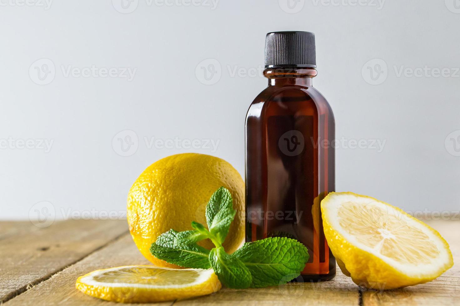 Aromatic oil with lemon and mint on wooden background. photo