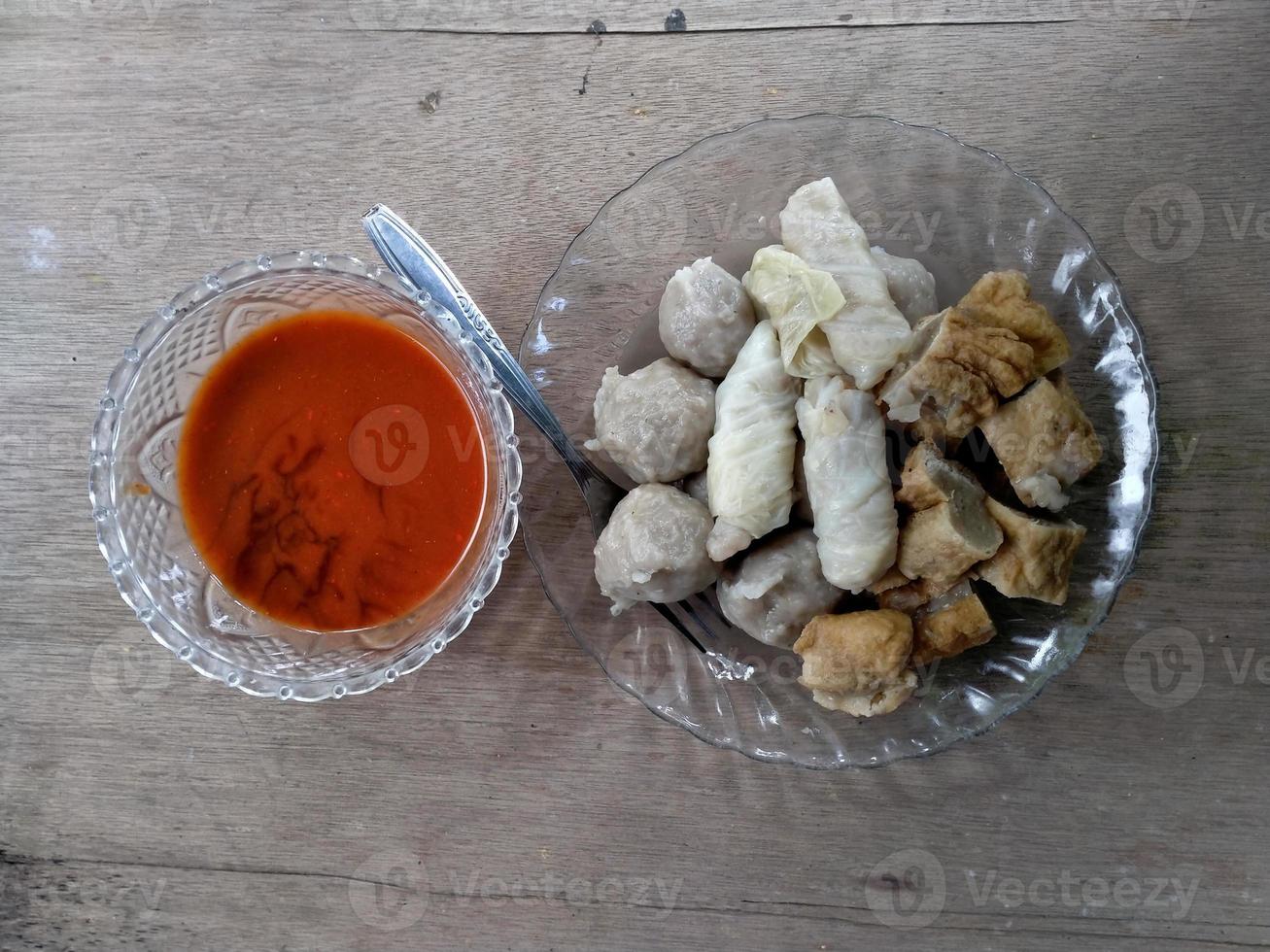 close up of meatball with sauce on plate. with a wooden background. photo