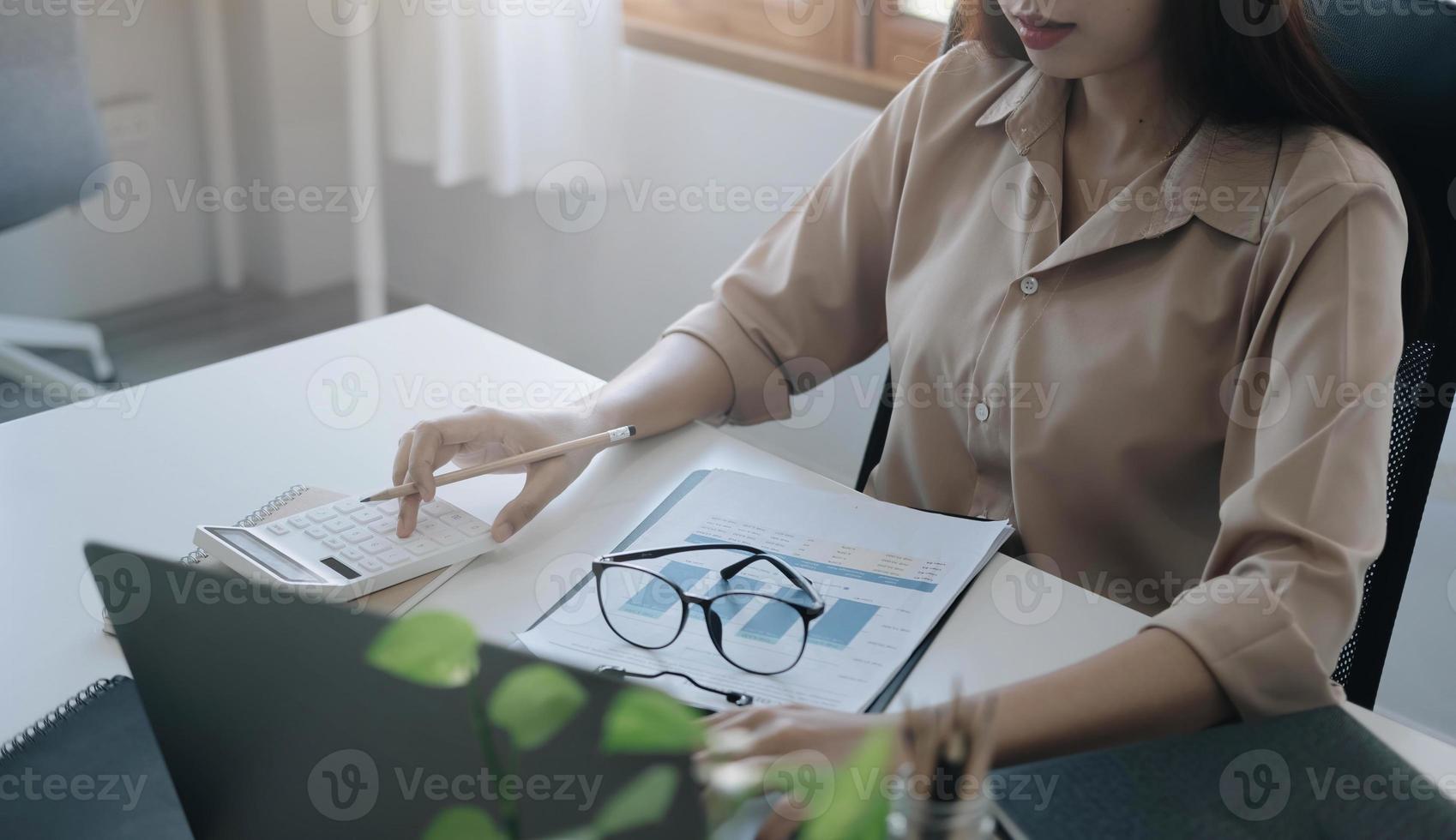 Mujer de cerca con calculadora y computadora portátil para calaulating finanzas, impuestos, contabilidad, estadísticas y concepto de investigación analítica foto