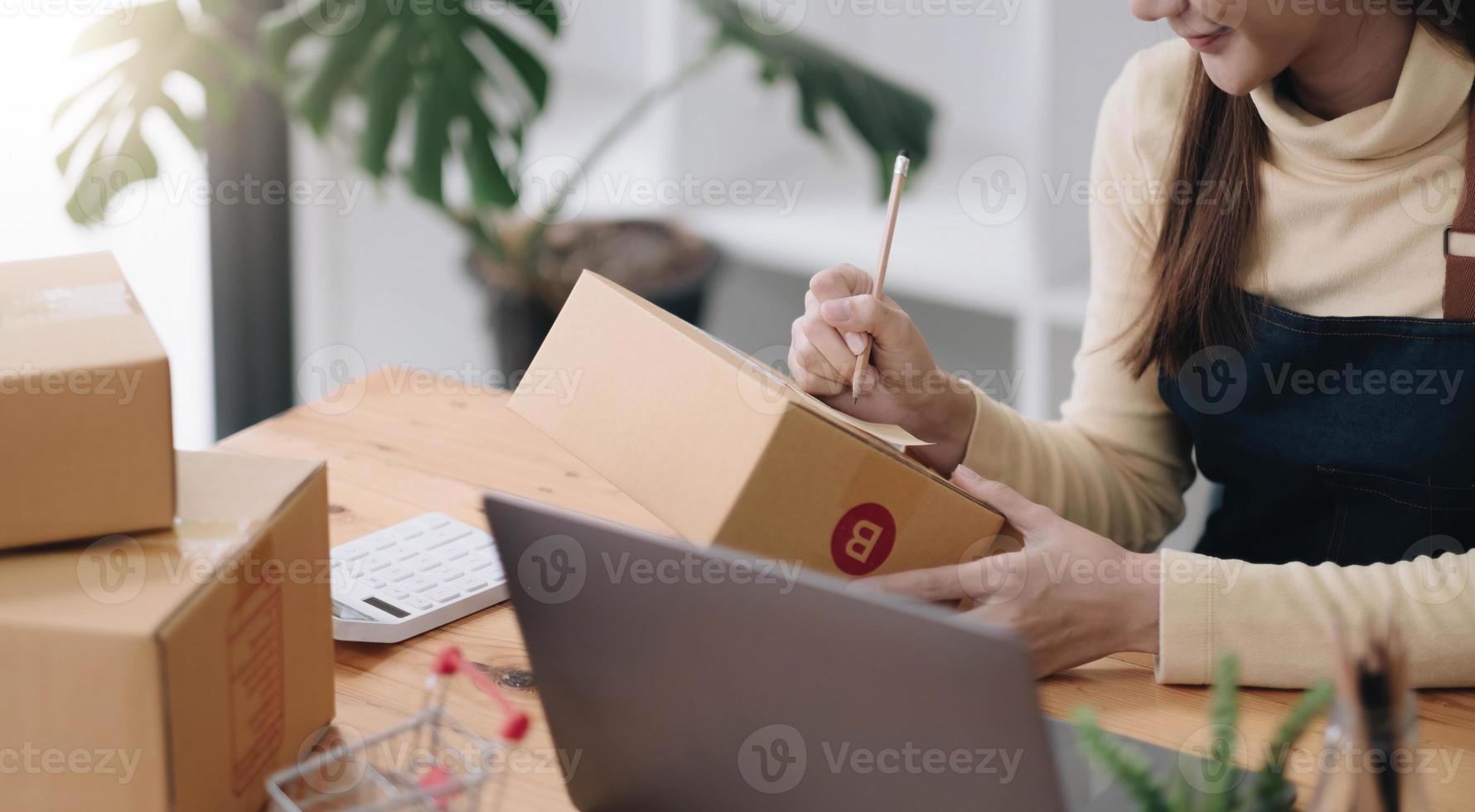 Starting small businesses SME owners female entrepreneurs Write the address on receipt box and check online orders to prepare to pack the boxes, sell to customers, sme business ideas online. photo