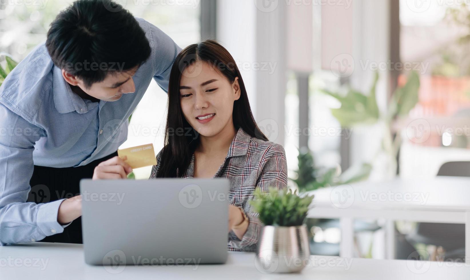 Young couple holding credit card and using phone. Online shopping, e-commerce, internet banking, spending money. photo