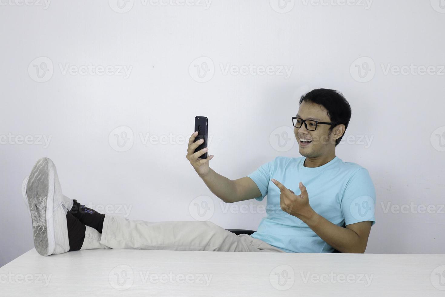 Young asian man shocked when he looking smartphone with leg on the table photo