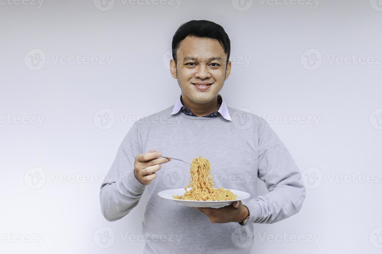 Portrait of happy Young Asian man enjoys noodles. Eating lunch concept. photo